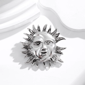 Elegant silver sun goddess face brooch with radiant rays on a white geometric display