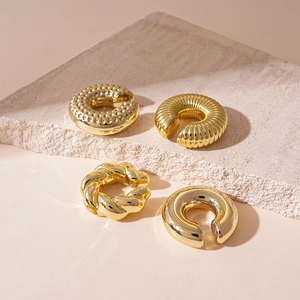 Macro shot of four gold-plated ear cuffs with hammered, pleated, and twisted metal textures