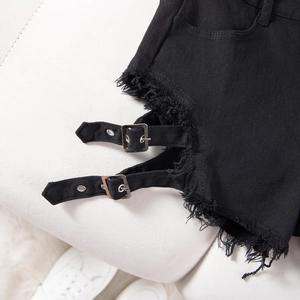 Detalle de pantalones cortos vaqueros negros con hebillas de metal y dobladillo deshilachado