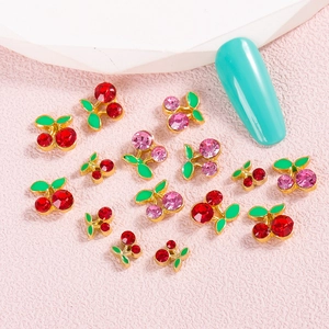 Sparkling cherry nail art charms with red and pink rhinestones on a metal base