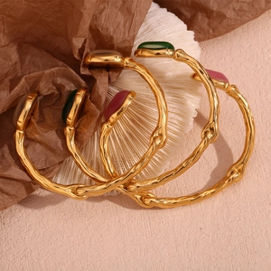 Detailed macro of gold plated bangles featuring green and pink oval natural stones