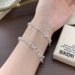 Detailed view of 925 sterling silver handmade woven chain bracelets on a wooden surface