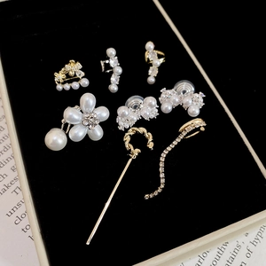 Détail des boucles d'oreilles fleurs perles dorées et zircons sur boîte en velours