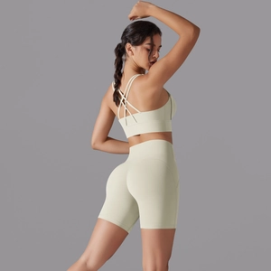 Dettaglio del reggiseno sportivo incrociato e pantaloncini da yoga a vita alta crema