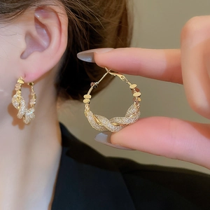 Macro detail of gold-plated twisted hoop earrings with micro-set shimmering rhinestones