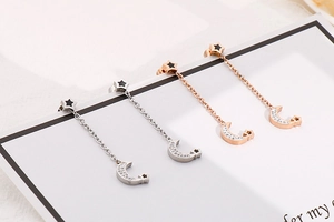 Detail of silver and rose gold star and moon drop earrings with sparkling rhinestones