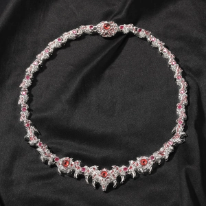 Macro detail of gothic claw necklace with red eyes and silver spikes on black fabric