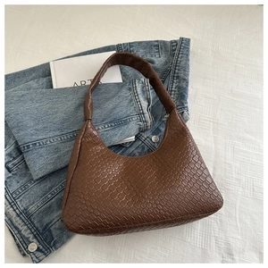 Detail view of woven leather texture on a dark brown shoulder bag with a stylish design