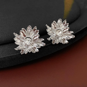 Macro shot of silver flower earrings with radiant petals and clear crystal center