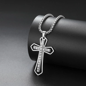 Close-up of a silver stainless steel cross pendant with white rhinestones and box chain