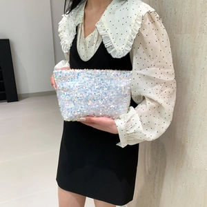 Fashionable sparkling sequin clutch bag held by model, perfect for evening parties