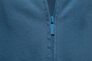 Close-up of smooth dark blue zipper and knitted texture on men's cotton V-neck T-shirt