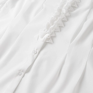 Close-up of elegant white chiffon blouse featuring ruffled trim and clear round buttons