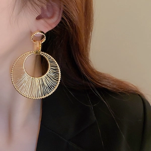 Detailed view of woven metal gold hoop earrings with intricate radial wire texture