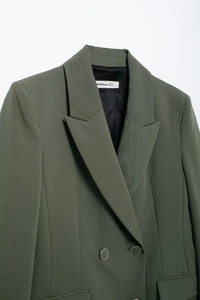 Détail du blazer croisé vert montrant les boutons argentés et l'étiquette de marque interne