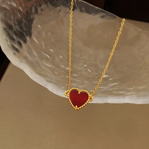 Detail of red heart pendant with gold beaded edges on a delicate gold chain necklace