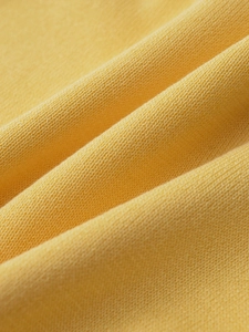 Close-up of ginger yellow knit polo shirt showing fine ribbed texture and soft fabric