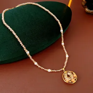 Elegant gold double-ring pendant necklace with opal and pearls on a green jewelry box