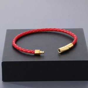 Détail du bracelet en cuir tressé rouge avec un fermoir magnétique en or poli