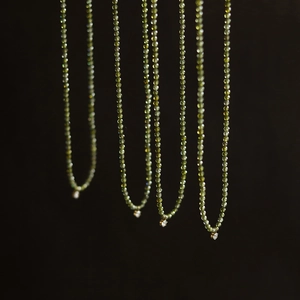 Detailed macro view of olive green beaded necklaces featuring sparkling zircon pendants