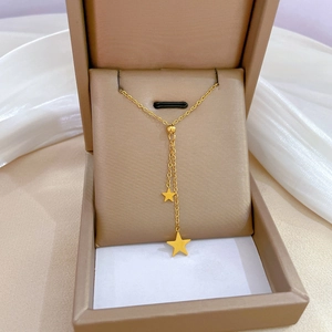 Detail view of a gold star tassel necklace in a premium beige jewelry box