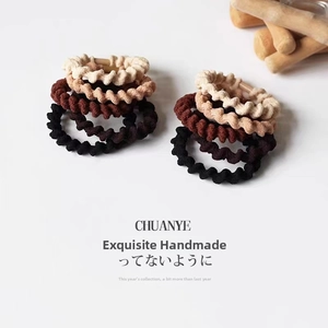 Close-up of eight fabric-wrapped spiral hair ties in neutral beige and black tones