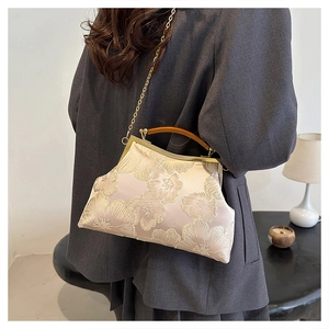 Close-up of champagne satin purse with 3D floral embroidery and faux wood handle