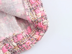 Gros plan sur la texture du tissu en tweed rose et gris avec fils dorés détaillés