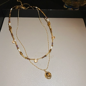 Detail of double-layer necklace with beaded chain and tiger eye stone pendant in 18K gold