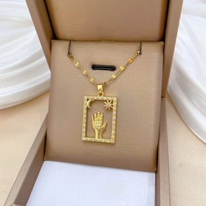 Macro shot of gold rectangle pendant with celestial palm, moon and stars inside a box