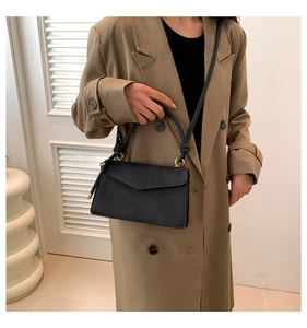 Détail d'un sac à main noir mat avec poignée à nœuds et accents métalliques dorés
