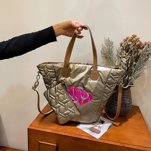Detail der champagnergoldenen Stepptasche mit rosa Herzaufnäher und passendem Etui