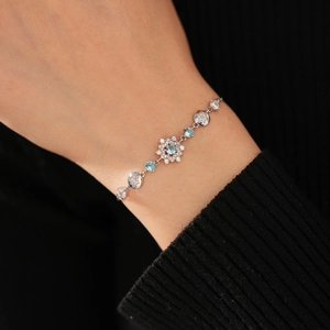Detailed close-up of a delicate snowflake bracelet with blue zircon and silver chain