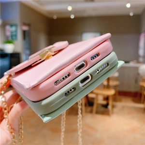 Close-up of pink and green leather phone cases with metal chains and precise port cutouts
