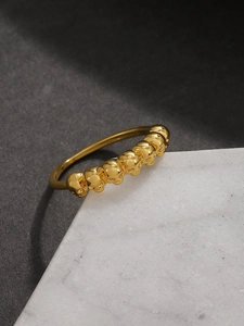 Macro di un anello gotico dorato con sette teschi disposti su base di marmo bianco