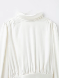 Détail du chemisier en satin blanc montrant l'encolure dos et les plis élégants du tissu