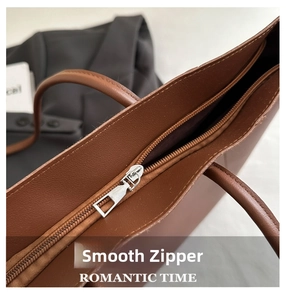 Detailed close-up of smooth metal zipper closure on the brown leather tote bag