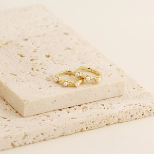 Close-up of S925 sterling silver hallmark on gold pearl earrings with sparkling diamonds
