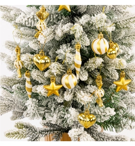Close-up of golden Christmas ornaments hanging on a snowy pine tree branch