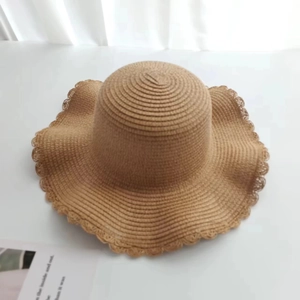 Detail of hand-woven straw hat featuring unique scalloped edges and a wide brim design