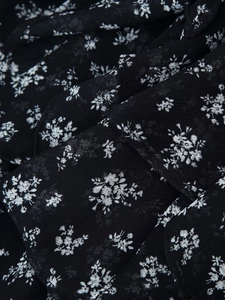 Détail du tissu en mousseline fleurie sur une robe courte noire à col en V