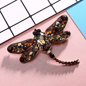 Macro detail of dragonfly brooch with amber rhinestones and a large faceted brown gem