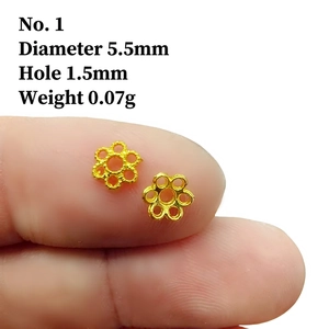 Macro shot of 5.5mm gold filigree flower spacers for DIY jewelry making on a finger