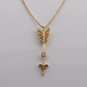 Macro detail of gold plated arrow pendant necklace with sparkling cubic zirconia crystals