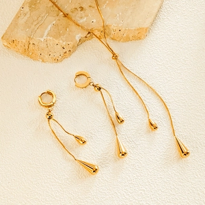 Detailed view of luxury gold teardrop necklace and matching tassel earrings set