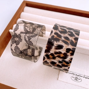 Detail of acrylic open bangles with leopard print and black lace floral pattern in jewelry box