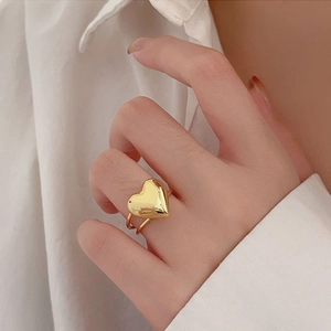 Macro detail of a golden heart ring with double-band design worn on a finger