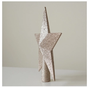 Close-up of glittery champagne gold Christmas tree topper star on a neutral background