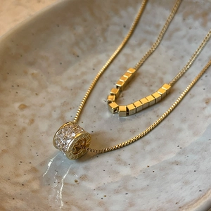 Double-layered gold necklace featuring a zircon barrel pendant and minimalist cube beads