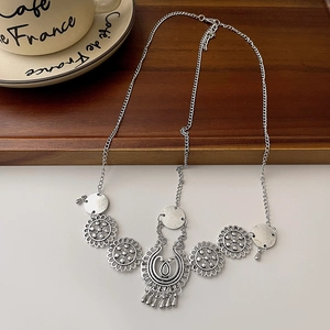 Close-up of silver vintage forehead chain with floral charms and tassel on wooden tray